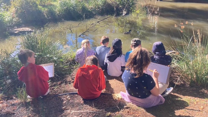 kids with pencils and paper observe a duck in the pond at CCC's Environmental Learning Center